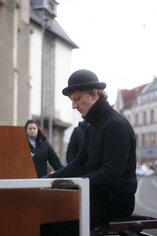 Mann mit Hut am Klavier im urbanen Umfeld